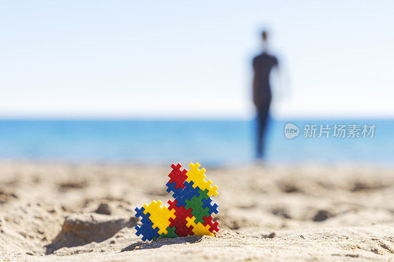 五颜六色的拼图自闭症意识心沙滩上的沙滩和背影看剪影的孩子走到海边的海洋