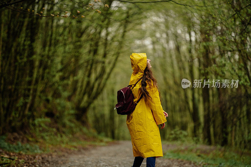 雨中穿着黄色雨衣的年轻女子