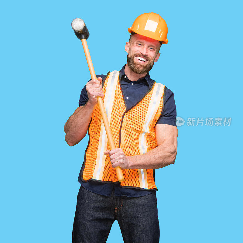 白人年轻男性建筑工人站着，穿着反光衣服，拿着锤子