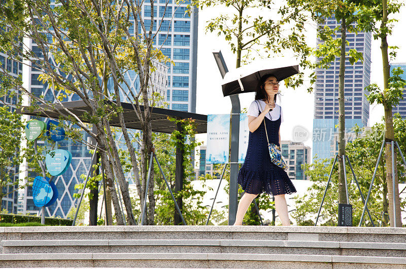 在中国深圳的深圳人才园，游客们打着雨伞躲避烈日。这个公共主题公园与深圳湾公园和湾体育馆相连