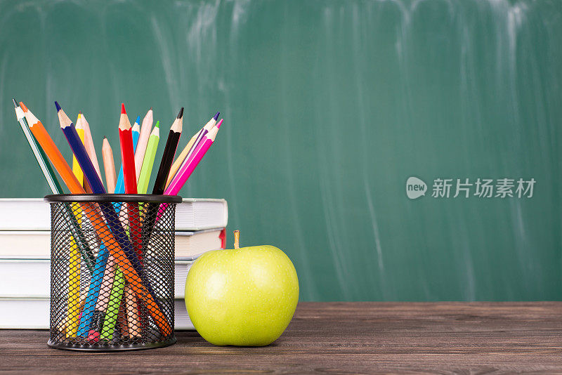 回到学校的概念。近距离照片彩色蜡笔绿苹果教科书孤立在绿色黑板copyspace