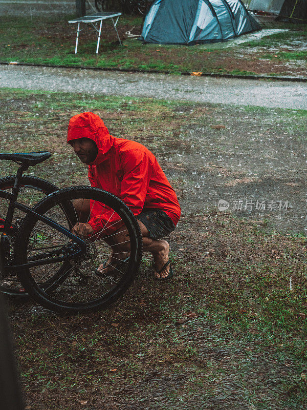 一名男子在暴雨中修理山地车