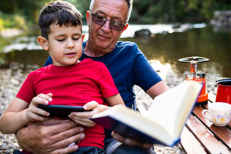 一个可爱的小男孩打断了他的祖父，给他看手机上的视频游戏