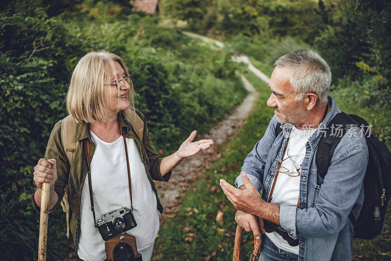 一对老夫妇在大自然中散步——一对快乐的老夫妇在美丽的健康之路上享受他们的假期