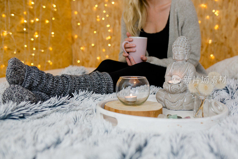 佛像和蜡烛在前景-女人正在喝茶休息
