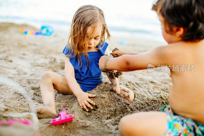 快乐的笑着蹒跚学步的男孩和女孩在沙滩上玩耍