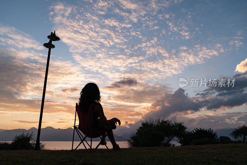 日落时坐在露营椅子上的女人剪影