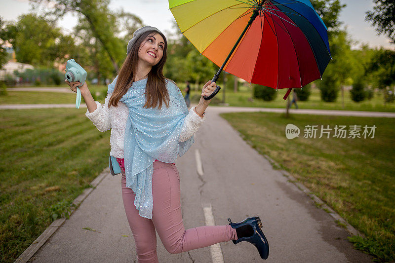 漂亮凉爽的女人带着五颜六色的雨伞在秋天的一天