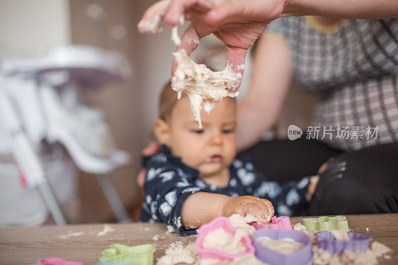 母亲和婴儿女孩玩面团成型的形状