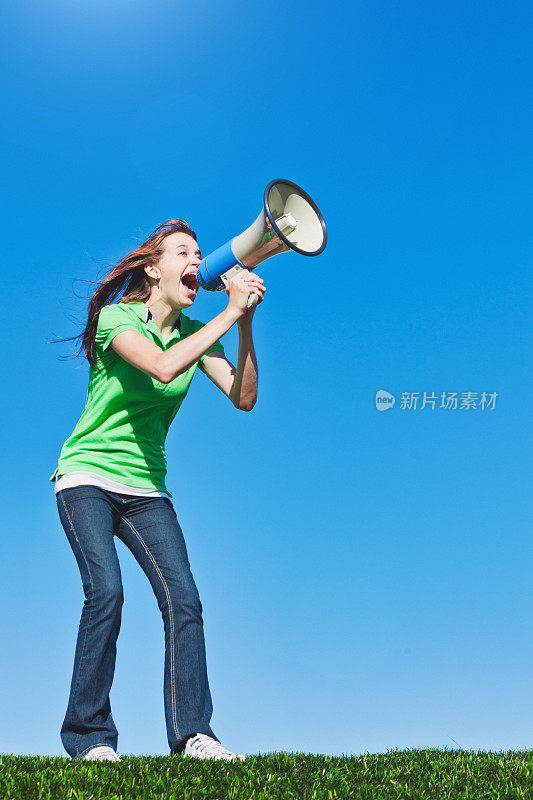 一个年轻女人对着扩音器大喊，对着晴朗的夏日蓝天