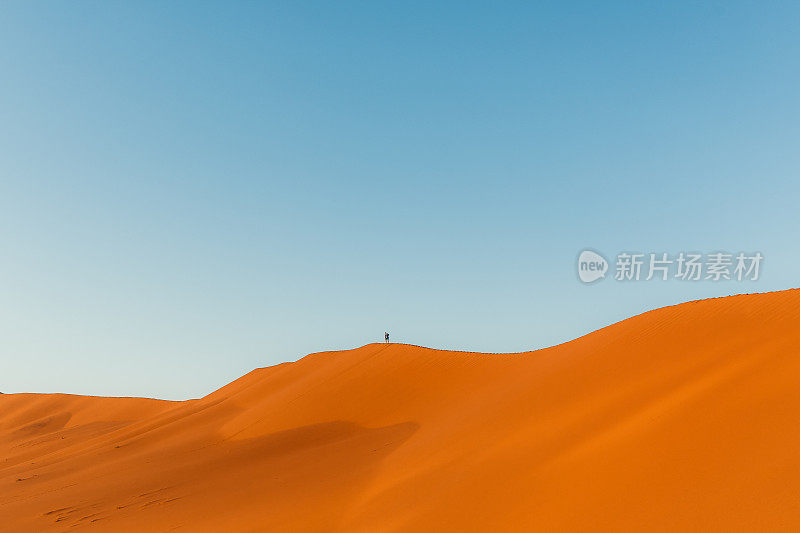 在纳米比亚的索苏雷，一名男子在沙丘顶上欣赏日出美景