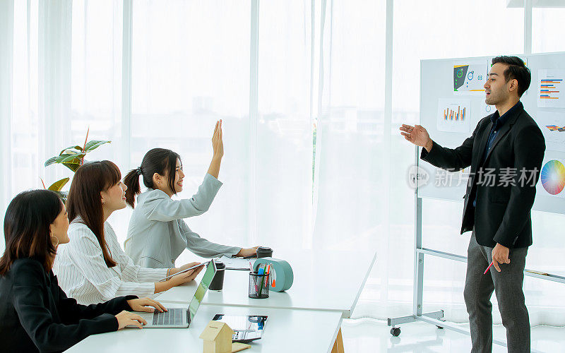 聪明的亚洲人在团队中进行正式的团队合作，聆听企业战略营销计划，在男经理或同事发言完毕后举手提问。