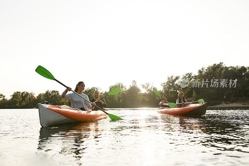 快乐的年轻人一起在河上划皮艇，在夏天的一天在户外度过周末