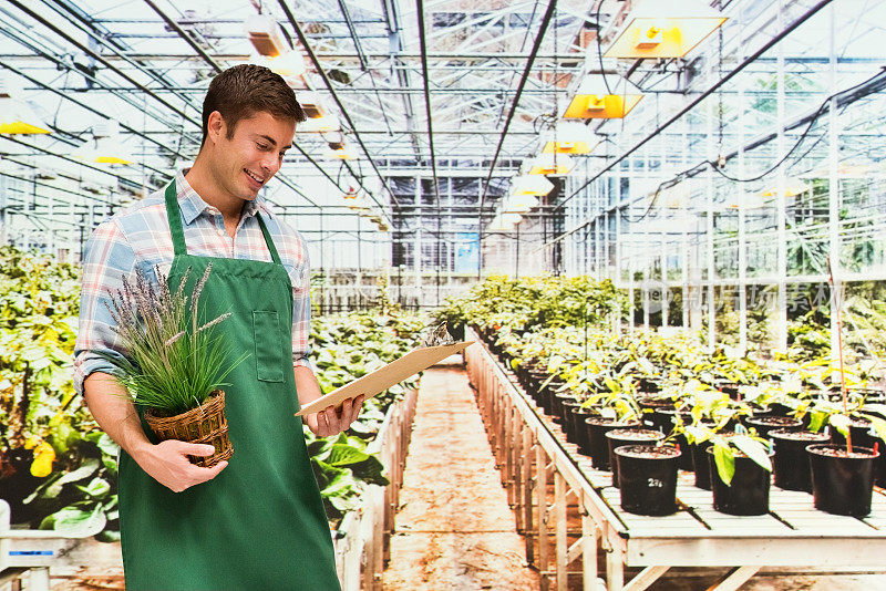 白人年轻男性花匠园艺穿着纽扣衬衫和持有文件