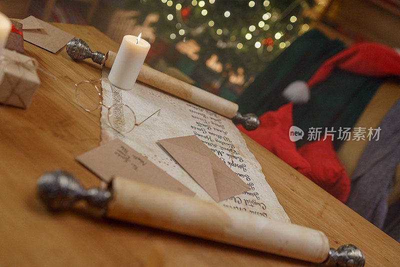 桌上放着一个古老的纸卷，上面写着孩子们的名字、圣诞老人的圆眼镜、信封和蜡烛