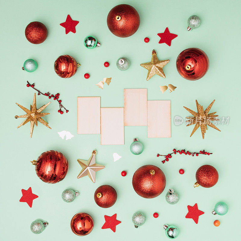 圣诞节装饰由闪亮的金色星星，红色和绿色的小玩意，铃铛，木制复制空间在柔和的绿色背景。生动快乐的新年。复古平铺风格。