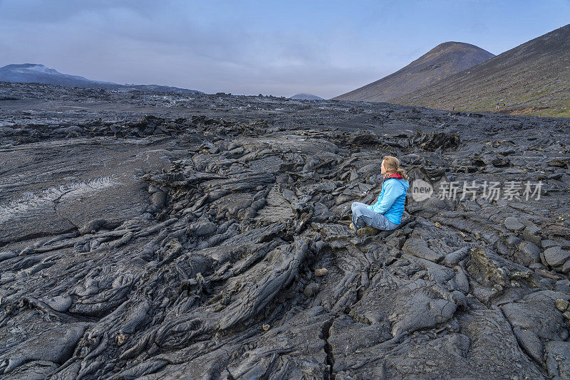 女人们坐在Fagradalsfjall火山冷却的黑色熔岩上