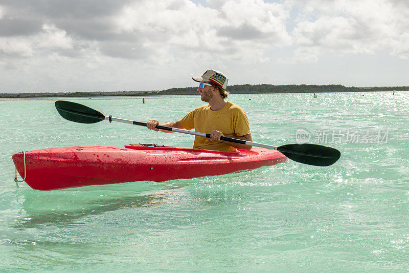 男游客在热带泻湖上划独木舟，享受国外的假期