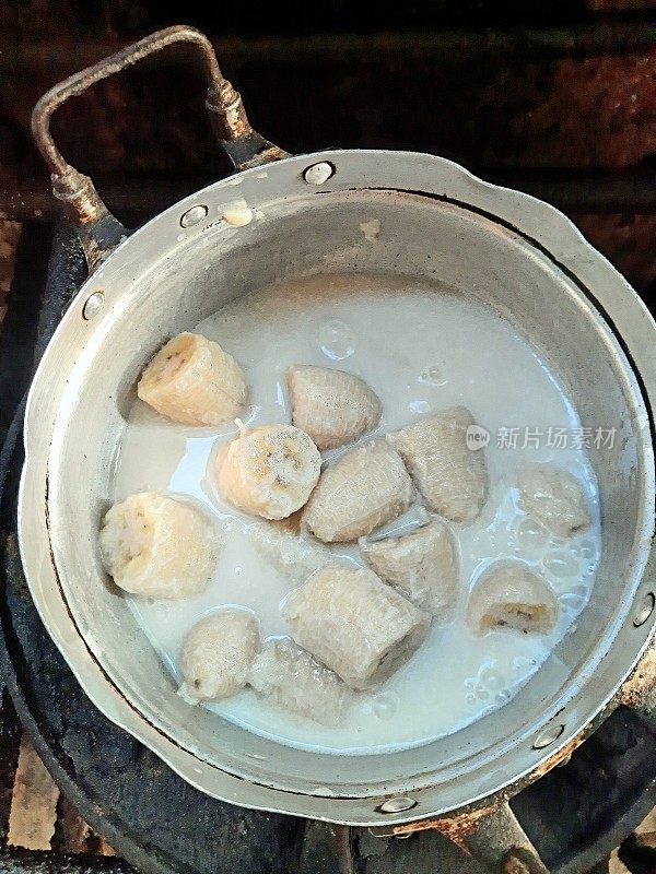 用椰子汁在炉子上煮香蕉，准备食物。