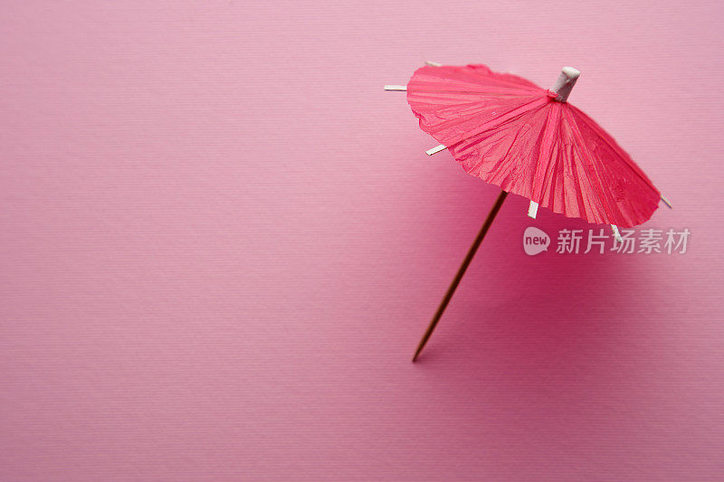 红色的鸡尾酒伞孤立在粉红色的背景上。