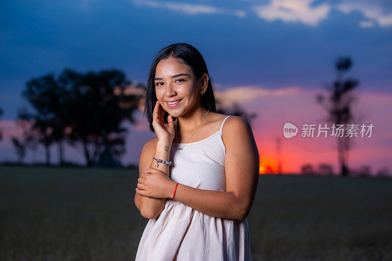 美丽的年轻女子享受日落。