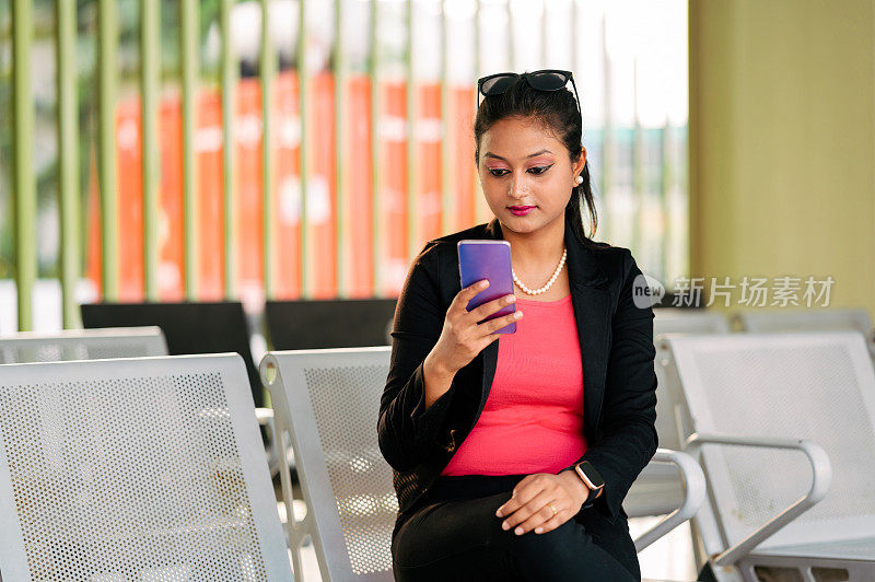 在公交车站用手机聊天的女人。