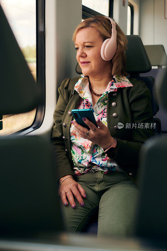 一个中年妇女，带着手机和耳机在火车上