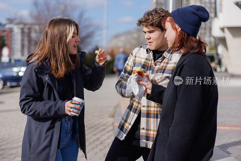 快乐的青少年朋友们站在户外休息，喝咖啡，吃零食