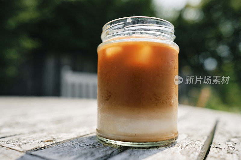 在一个炎热的夏日，破旧的花园桌子上放着冰拿铁。