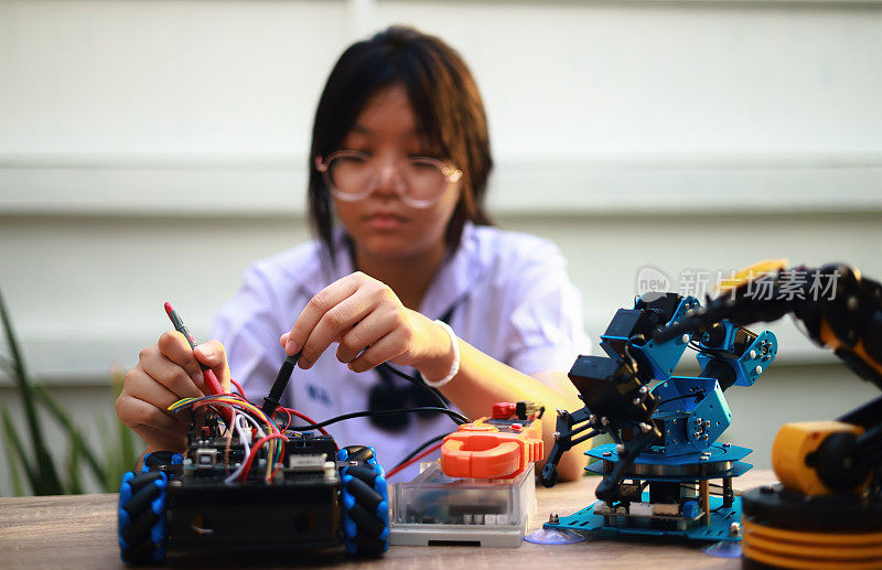少女用万用表检查机器人学习KIT，科技学习概念，少女用万用表检查电路板