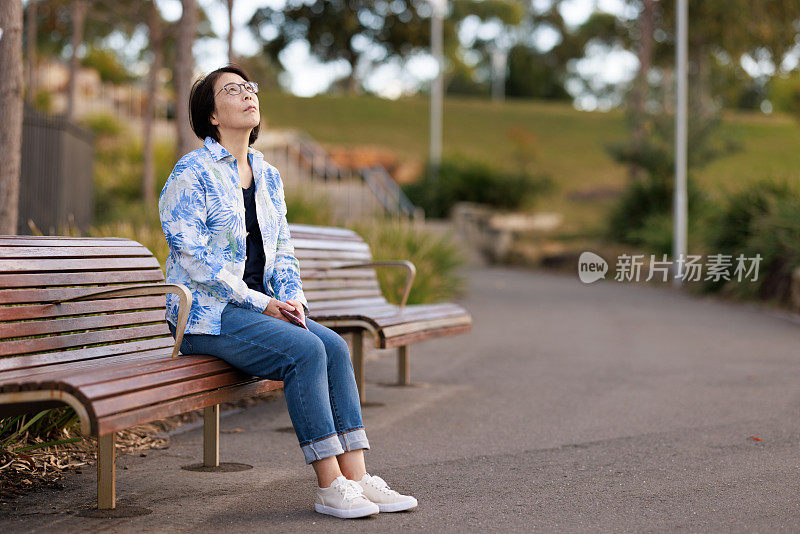 亚洲妇女在户外的长凳上休息