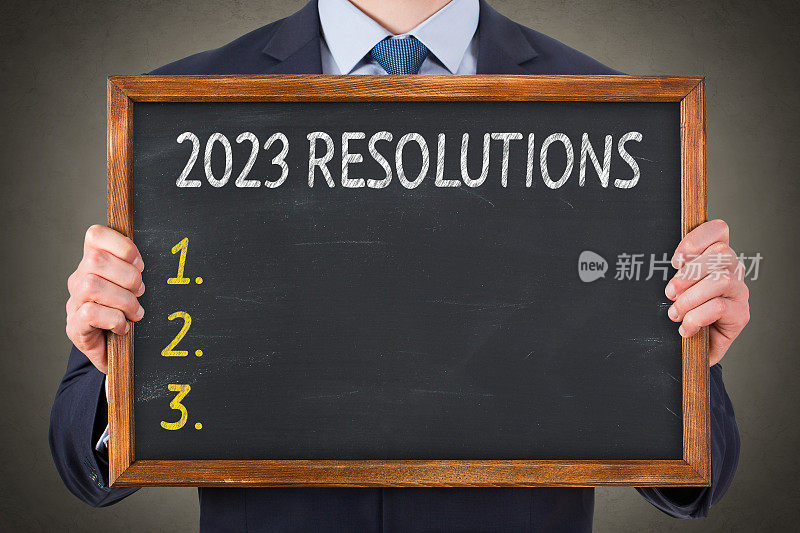商务人士在黑板背景上写2023年新年决心