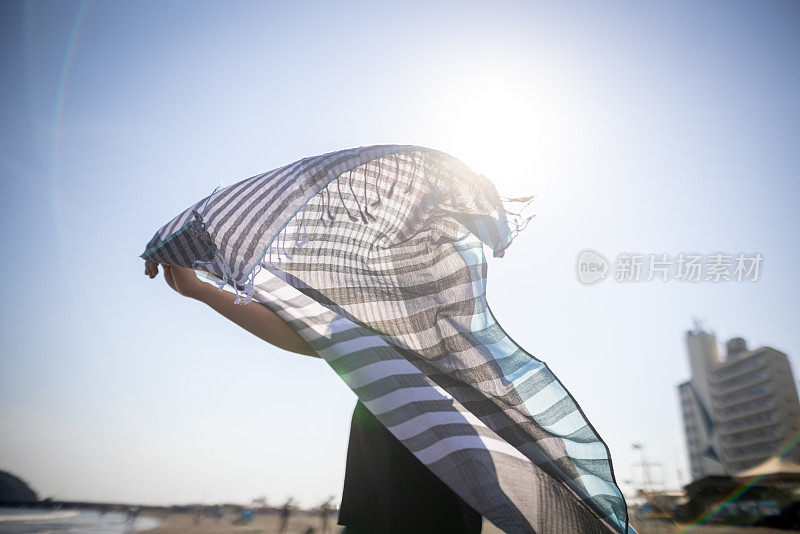 快乐的女人跳舞与围巾在海滩-后视图