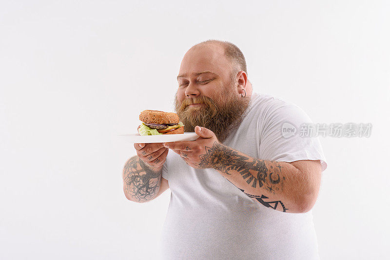 快乐的胖子享受着不健康的汉堡