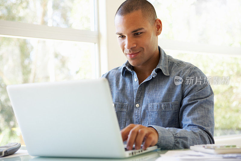 一个年轻人坐在桌子旁用着笔记本电脑