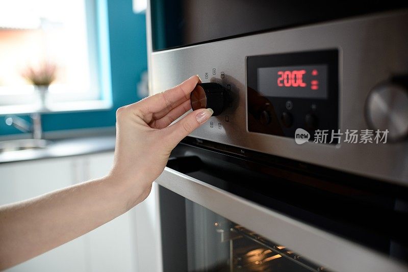 关闭女人的手设置温度控制烤箱