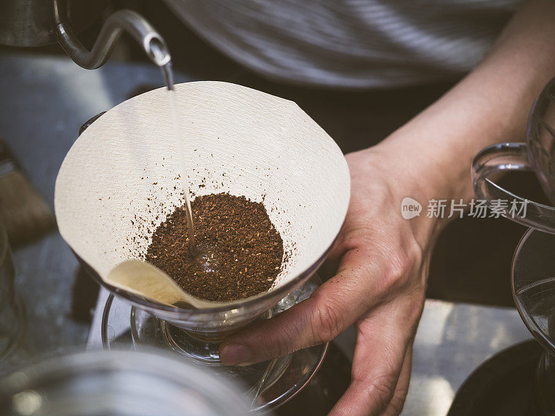 咖啡师将水倒在咖啡地上，用手滴咖啡