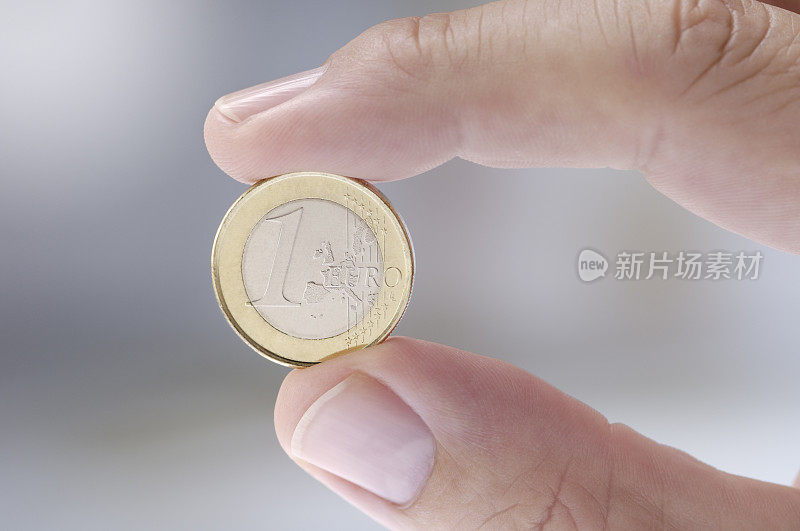 用两个手指夹一枚欧元硬币