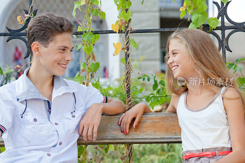 一对快乐坦诚的青少年情侣看着对方的眼睛，在户外微笑