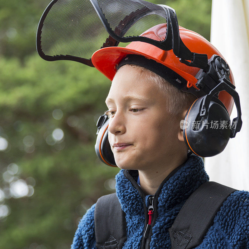 年轻严肃的男孩戴着防护头盔和耳罩