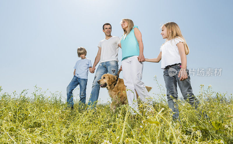 下图是一家人在大自然中带着狗散步。