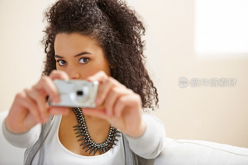 这位年轻女士正在用数码相机给你拍照