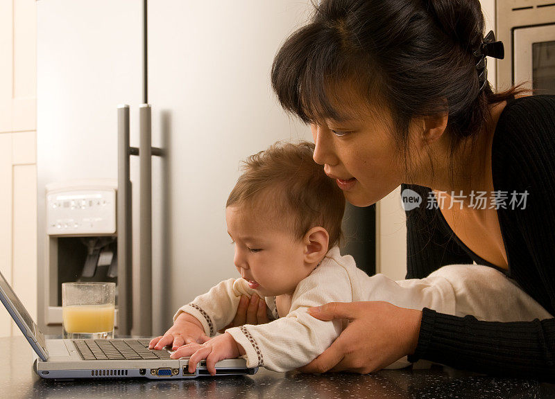 年轻的母亲在电脑上和婴儿玩