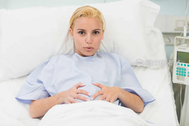 孕妇躺在床上，抚摸着自己的肚子