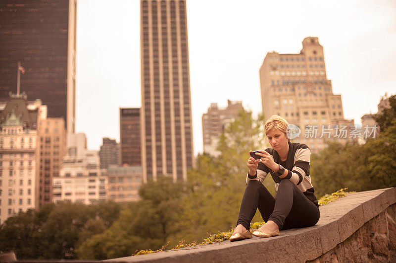 坐在中央公园拿着智能手机的女人
