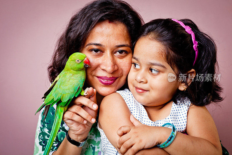 印度母亲女儿和绿色鹦鹉坐在她的手上