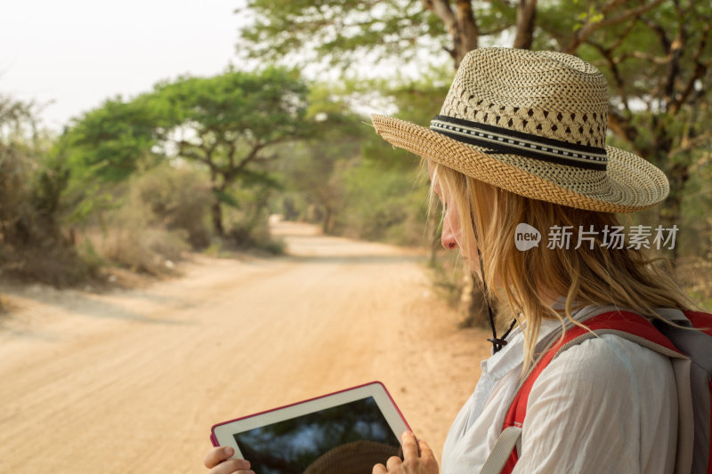 一名女游客在沙漠路上用着平板电脑