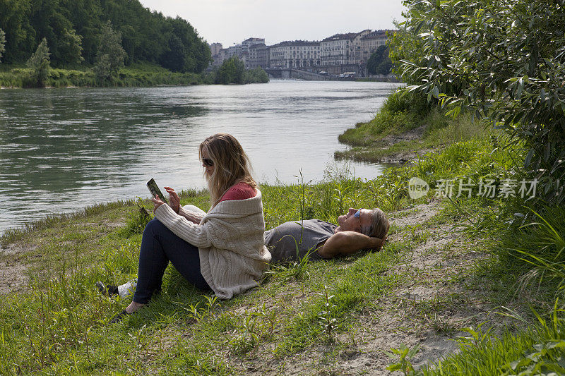 女人在河上用平板电脑，男人放松