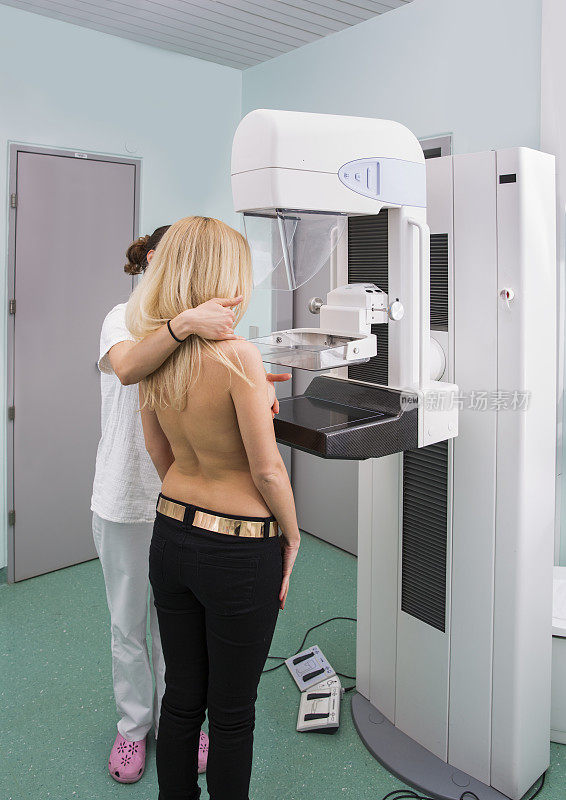 x光技术员正在给一位年轻女性做乳房x光检查