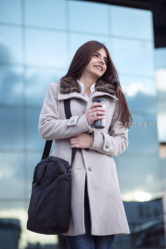 微笑的女人在办公大楼前的咖啡休息